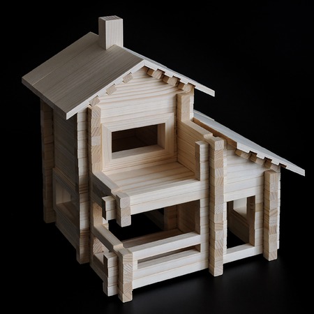 Little wooden house with natural colored toy blocks on black backgroundの写真素材