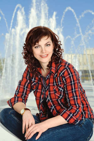 studio portrait of a smiling brunette woman posing outdoors and looking at cameraの写真素材