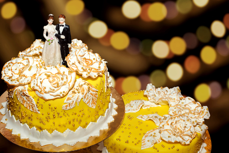 Sweet wedding cake decorated with figures of the newlyweds, Bokeh background.の写真素材