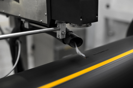 Industrial laser engraving on a plastic pipe. Tube rolling plant.の写真素材