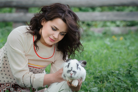 Portrait of a beautiful girl in Slavic clothes. Young woman with a rabbit. Summertimeの写真素材
