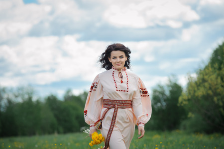 Portrait of a beautiful girl in Slavic clothes with a bouquet of dandelions. Summertimeの写真素材