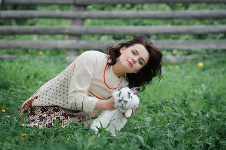 Portrait of a beautiful girl in Slavic clothes. Young woman with a rabbit. Summertimeの写真素材