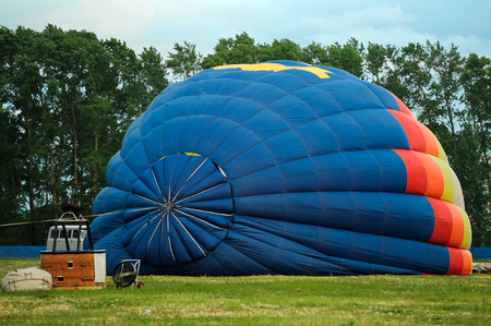 Colorful hot air balloon being inflated on the ground and getting ready for flightの写真素材