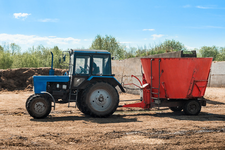Tractor working on farm. Blue tractor pulling red trailer. Agricultural machineの写真素材