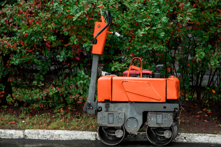 Small asphalt paver for sidewalk. Red road roller ready for repair roadsの写真素材