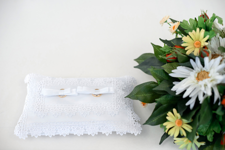 Two gold wedding rings on a white lace pillow. Place for textの写真素材