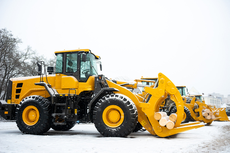 Yellow wheel front end log loader. Forestry equipment for moving wood and other materials. Hydraulic manipulator. Heavy diesel tractor, industrial machinery. Winter timeの写真素材
