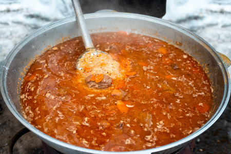 Cooking delicious pilaf in big cauldron outdoors. National Uzbek cuisine, a dish of rice, meat, vegetables and spices. Street foodの写真素材