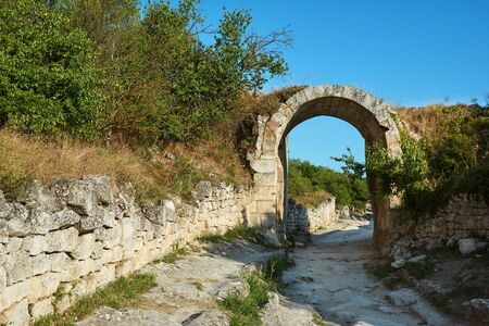 Stone arch on the street of an ancient abandoned city. The ruins of the old city. Sunny summer day, clear blue sky.の写真素材