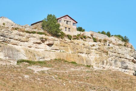 Ancient abandoned building on a cliff top. Stone house over a cliff. Sunny summer day, clear blue sky.の写真素材