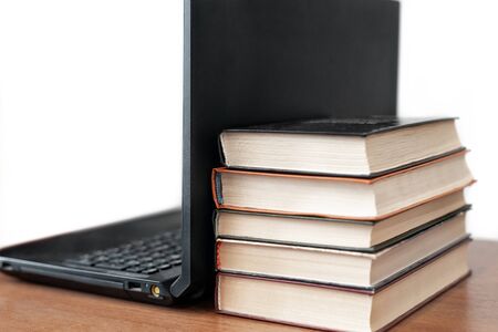 Stack of old books and modern laptop on wooden table. Modern technologies in education, teaching, reading. Online education, e-learning conceptの写真素材