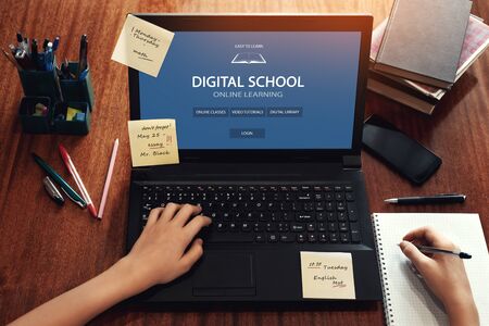 Student using computer to study on the Internet at home and taking notes. Online learning website page in a laptop screen. Distance and e-learning education concept. Modern technologies in educationの写真素材