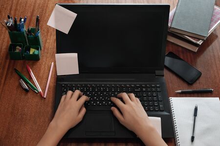 Top view of hands with laptop. Student using computer and typing on a keyboard. Distance and online education concept. Modern technologies in education. Blank screen for your ideasの写真素材