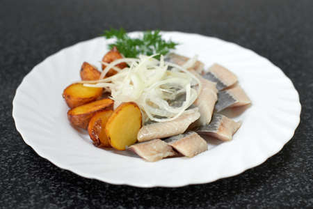 Pieces of salted herring fillet with baked potatoes and onionsの写真素材