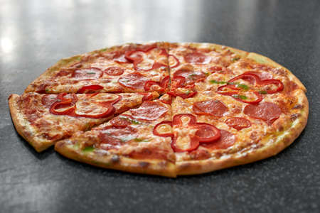 Delicious pizza with salami, red pepper and tomatoesの写真素材