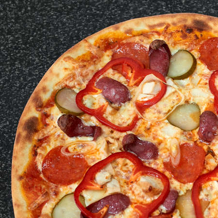 Delicious pizza with sausage, chicken, red pepper, pickles and onionsの写真素材