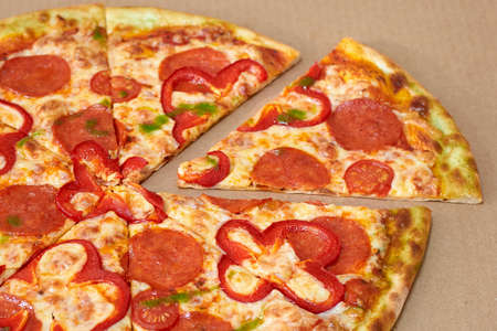 Sliced pizza with salami, red pepper and tomatoesの写真素材