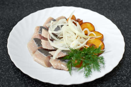 Pieces of salted herring fillet with baked potatoes and onionsの写真素材