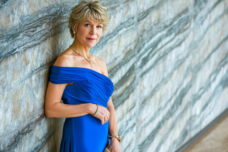woman with short, straight blonde hair and a heart-shaped face. She is wearing a blue, off-the-shoulder evening gown with a sweetheart neckline.の素材