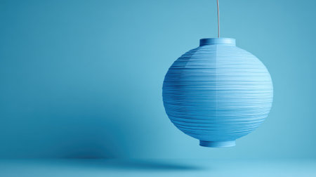 A round blue lantern gently hangs against a light blue backdrop adding tranquility to the scene.の素材