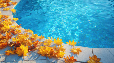 Golden autumn leaves cover the edge of a vibrant blue swimming pool. The water glistens under the sun creating a tranquil scene for relaxation.の素材