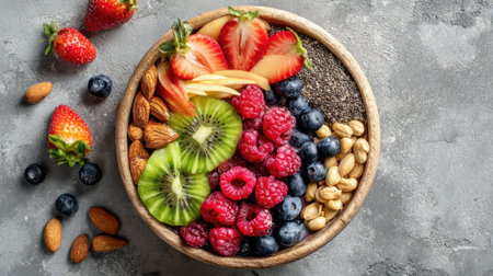 A vibrant bowl filled with sliced strawberries, kiwi, raspberries, and blueberries, alongside nuts arranged neatly. The fresh fruits and nuts create an inviting healthy snack.の素材