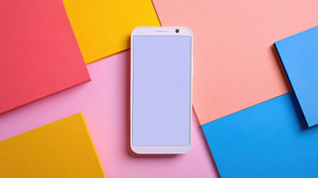 A sleek smartphone rests on a bright arrangement of colorful squares in pink, blue, red, and yellow. This lively setup creates an inviting atmosphere for creativity and productivity.の素材