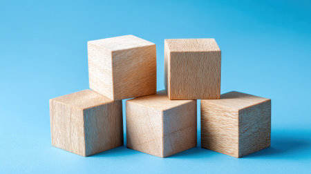 A set of wooden blocks is arranged in a playful manner on a bright blue surface. The blocks offer a simple design, suitable for fostering creativity in children during playtime.の素材