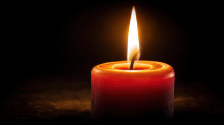 A single red candle burns brightly in a dark setting casting soft light and shadows. The flickering flame creates a serene and inviting ambiance perfect for meditation or quiet moments.の素材