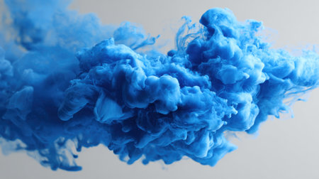 Blue smoke bills and twists in the air forming captivating patterns. The vibrant hue contrasts against a light background showing a mesmerizing artistic expression.の素材