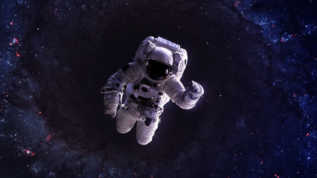 An astronaut floats above Earth. Stars provide the background. の写真素材