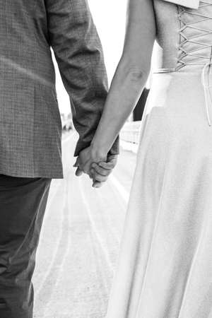 Bride and groom holding hands on the bridge, black and white photoの写真素材