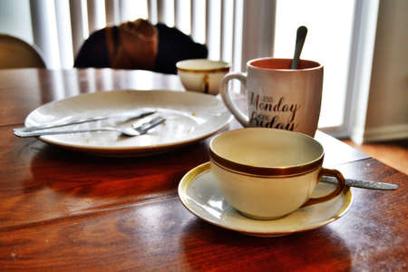 Table setting with a dirty plate and couple of cups left after lunch on the tableの写真素材