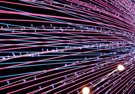 Glowing pink and light blue lights run horizontally with dark background.の写真素材