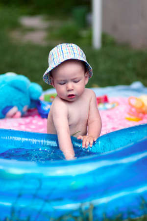 Little baby playing with toys in inflatable pool in the summer sunny dayの写真素材