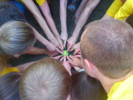 Top view of happy group of young people putting hands together showing finger gesture.Many hands pointing with their fingers to the center on green sphere.Team showing unity with their hands.
の写真素材