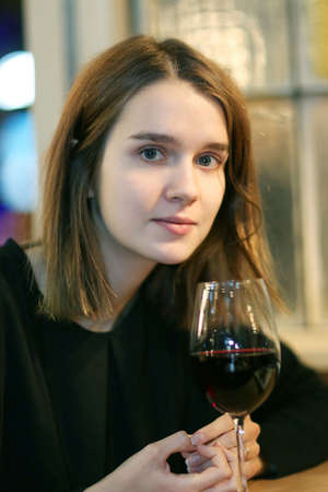 Portrait of elegant charming young glamour woman in restaurant with glass of red wineの写真素材