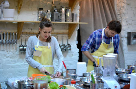 Two happy man and woman cooking and talking in the kitchen. Culinary, food and people conceptの写真素材