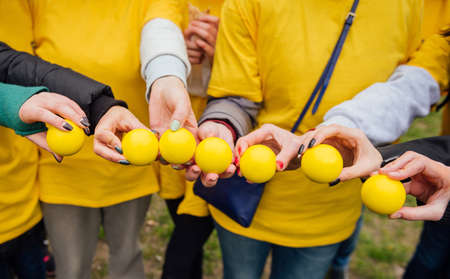 Yellow balls in the hands of beautiful women in row. Closeup, Shallow DOFの写真素材