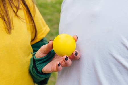Colorful background of people in yellow and white tee shirt with a hand holding a yellow ball. Shallow DOFの写真素材