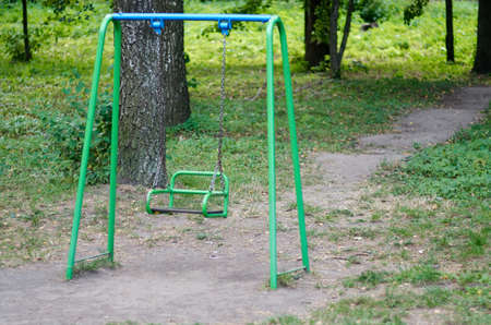 A swing on a playground in an outdoor setting or park.Swing in children playground surrounded by green.の写真素材