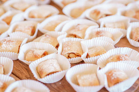 Set of  homemade fresh cookies dusted powdered sugar in white paper wrapper on wooden...