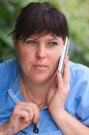 Young woman in blue blouser is talking on the phone.Girl Using Cell Phone outdoorの写真素材