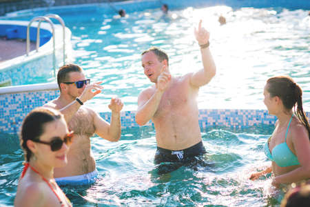 Group of cheerful young people having fun,dancing and partying at swimming pool.Summer vacation,celebration concept.Friends togetherの写真素材
