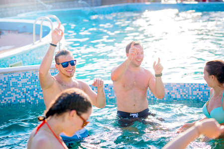 Group of cheerful young people having fun,dancing and partying at swimming pool.Friends together.Summer vacation,celebration conceptの写真素材