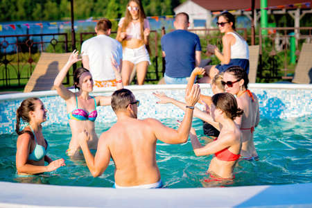Group of cheerful young people having fun,dancing and partying at swimming pool.Friends together.Summer vacation,celebration conceptの写真素材