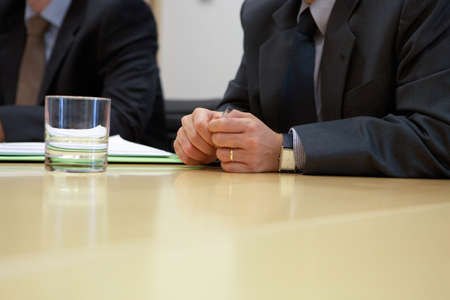 Businessman sitting at the desk and holding pen in hands.Business people working around table in...