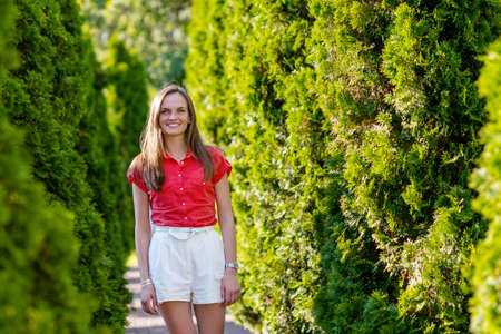 Portrait of happy young woman in white short and red blouse walking in summer park,outdoor.Positive human emotions,lifestyle and people conceptの写真素材
