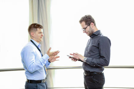 Two young businessmen interacting at meeting in officeの写真素材